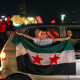 A young boy holds a Syria flag from a car in Damascus' Omeyyad square